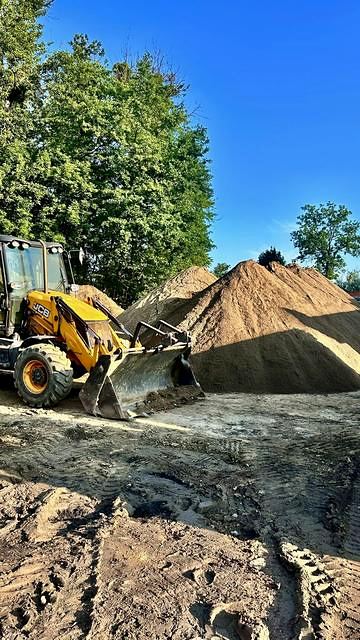 Koparko-ładowarka JCB przy hałdach ziemi